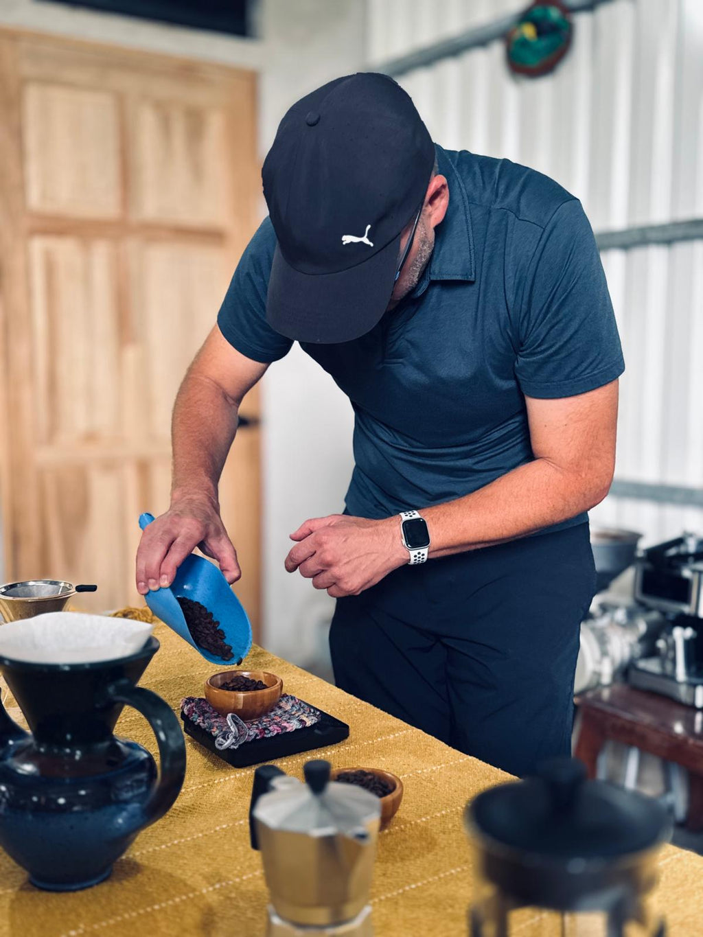 Man in a kitchen preparing coffee using a pour-over method.